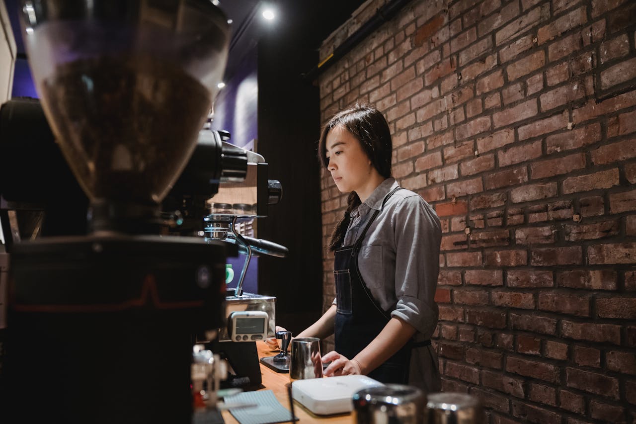 about-02 Barista preparing coffee at a café with brick wall ambiance and espresso machine.